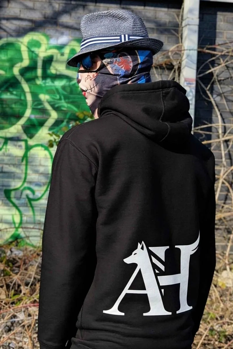 Albert Harry Dire Wolf Clan Royal Seal black organic hoodie — Sun & Spirit Walkers standing with black wolf against Manchester graffiti wall — independent UK streetwear 2026