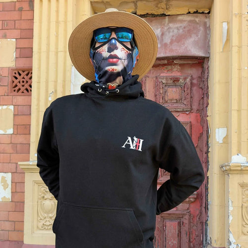 The Sun Walker, wearing an Albert Harry AH minimal White Knight black hoodie, sunglasses, and a straw hat, stood against the red wooden door of the Trafoord Park Hotel.